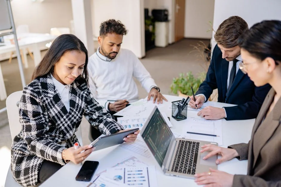 Un espace de travail moderne où des mains examinent des données marketing sur un ordinateur portable et des documents papier.